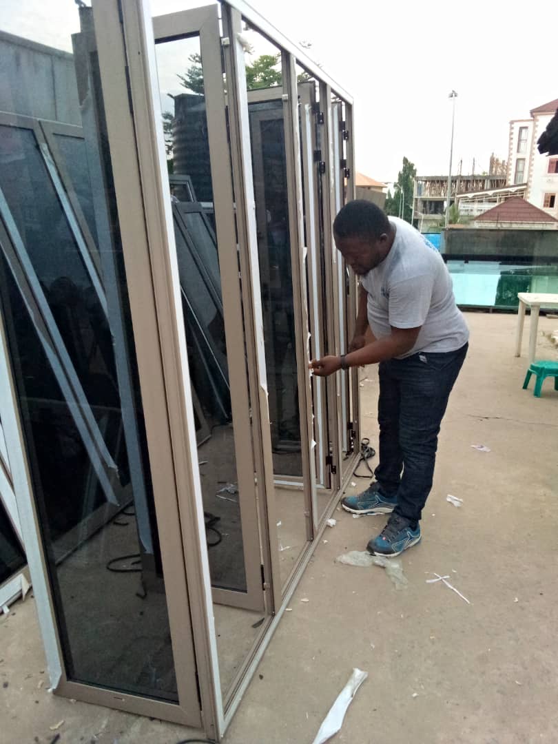 OSAFURE team member inspecting tall aluminium frames with tinted glass