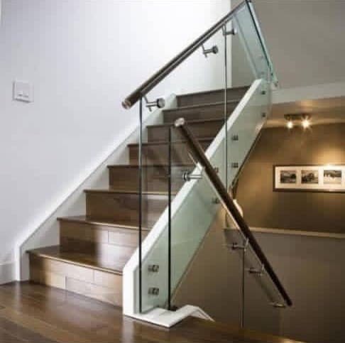 Glass staircase railing with a wooden handrail on steel brackets