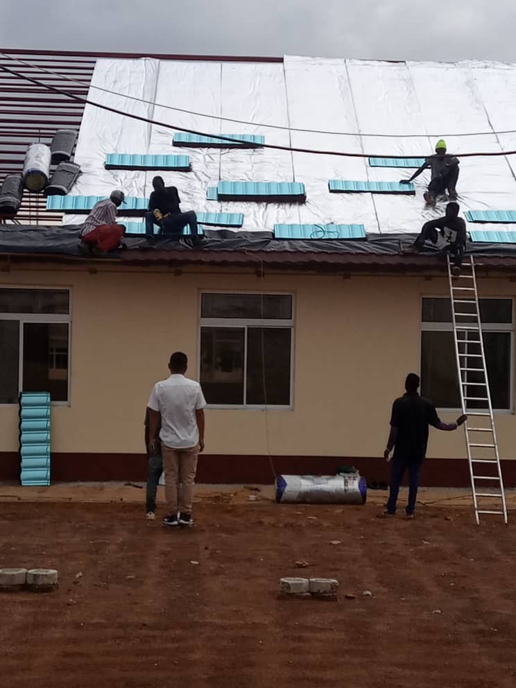 Roofing sheets and insulation being installed on a single-storey building