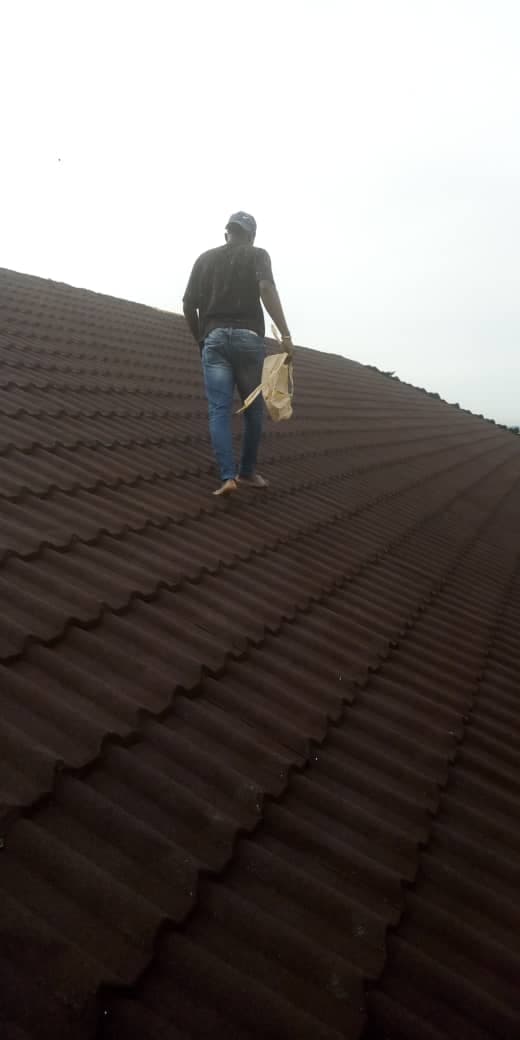 Worker on a newly fitted brown roofing-sheet roof