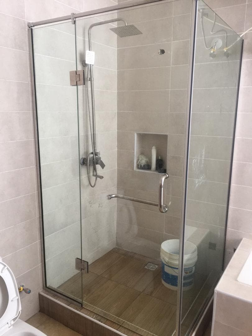 Glass shower enclosure with chrome fittings in a tiled bathroom