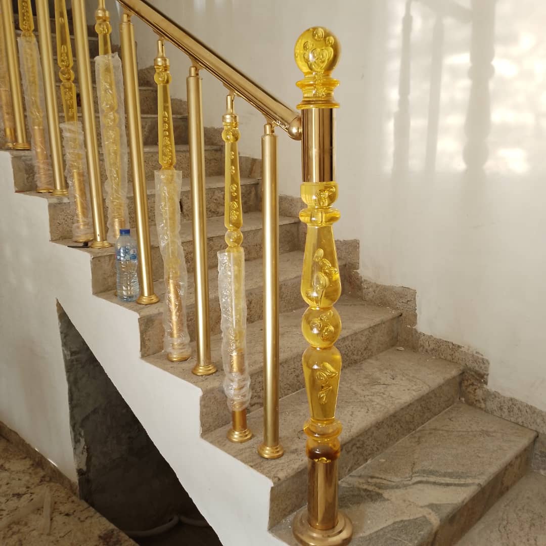 Gold-finish staircase railing with decorative clear balusters