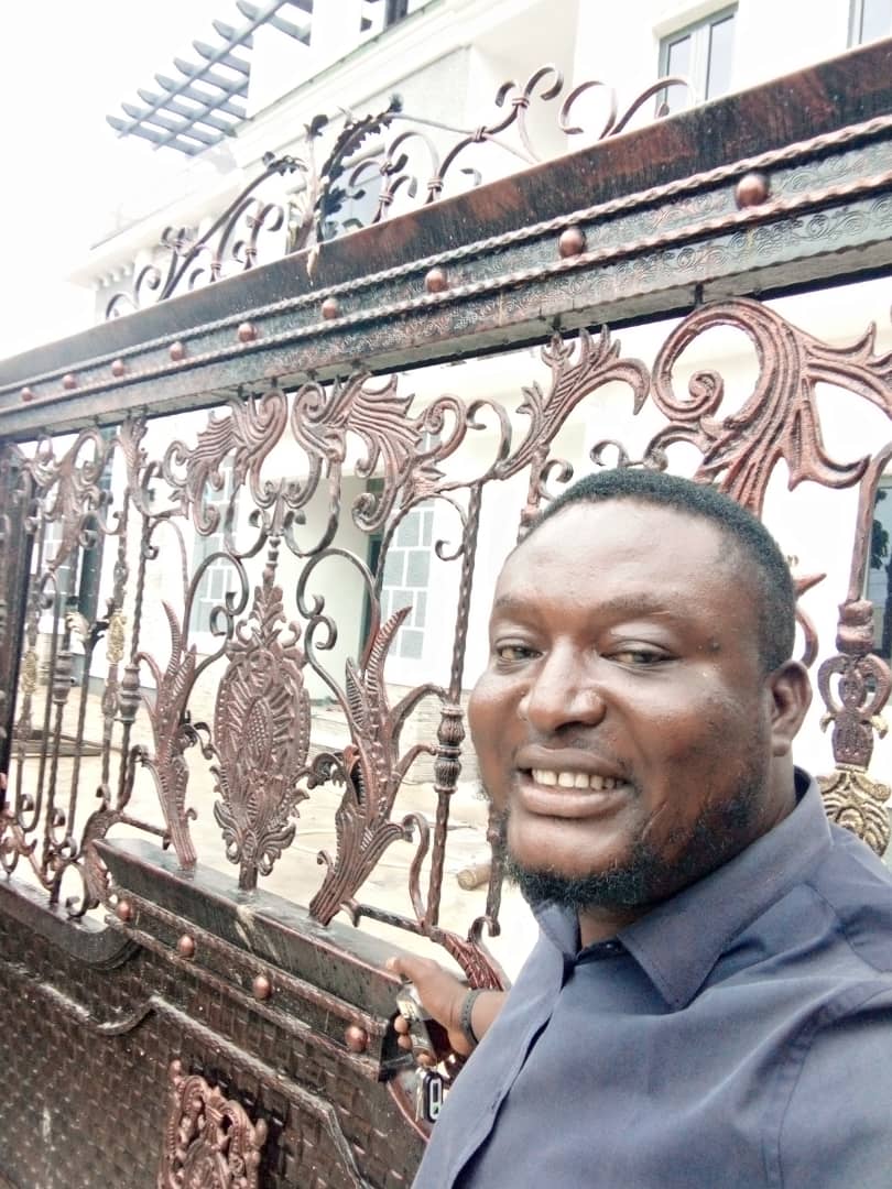 OSAFURE team member beside an ornamental metal gate