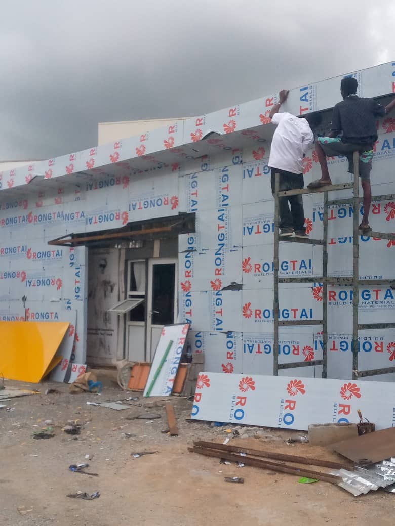 Workers fitting protective-film cladding panels to a building front